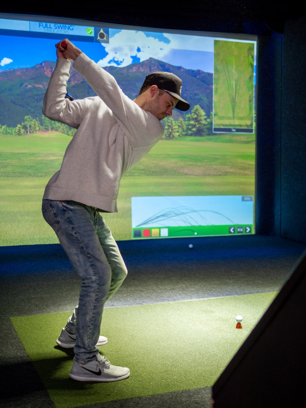 A golfer at the top of his backswing with TaylorMade clubs in the simulator bay