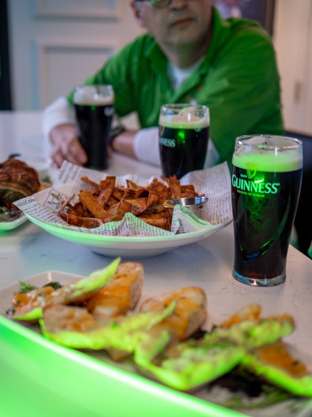 Guinness pints, wings and appetizers glowing over the lime-lit bay rail