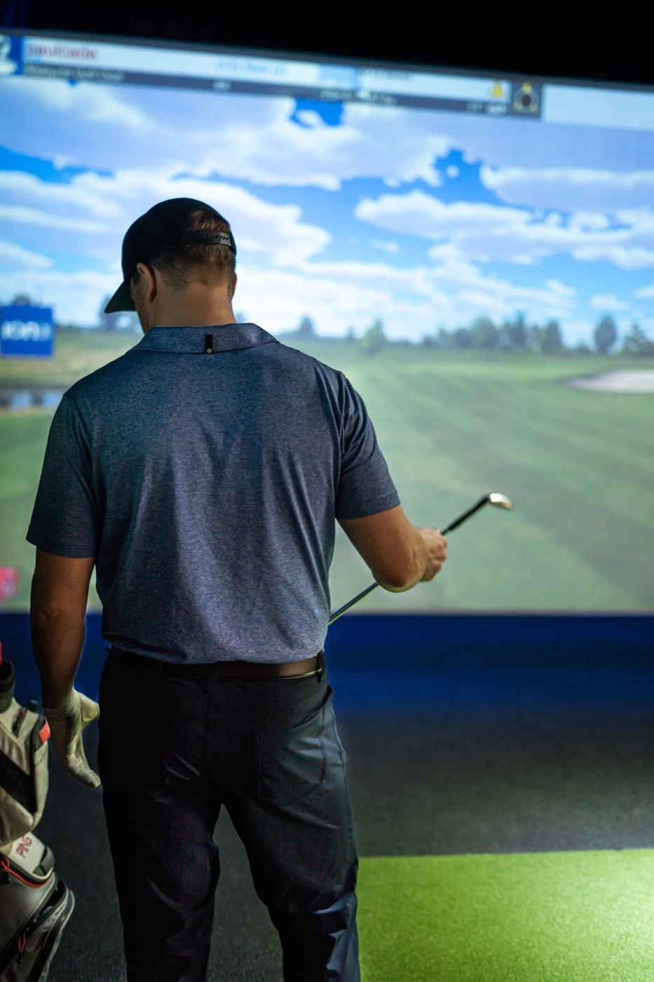 A golfer picks his club in front of the FullSwing screen