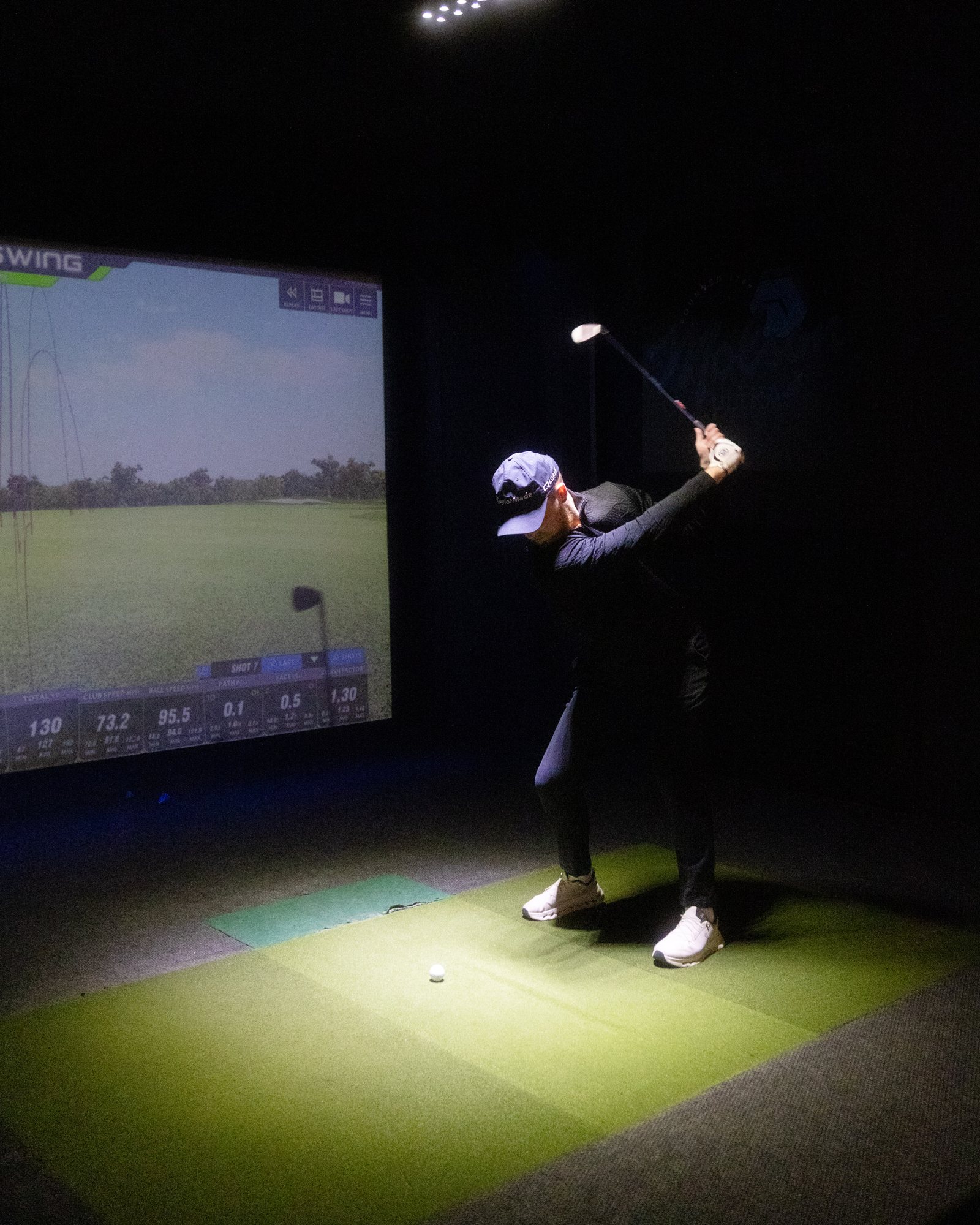 A league player drives under the lights inside a FullSwing simulator bay at Niagara Golf and Sports Lounge