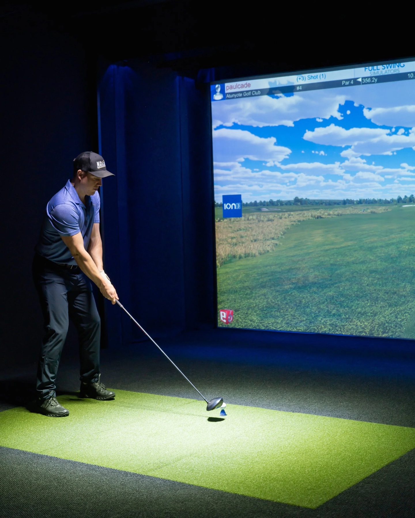 A golfer drives inside the FullSwing bay under a single pool of light