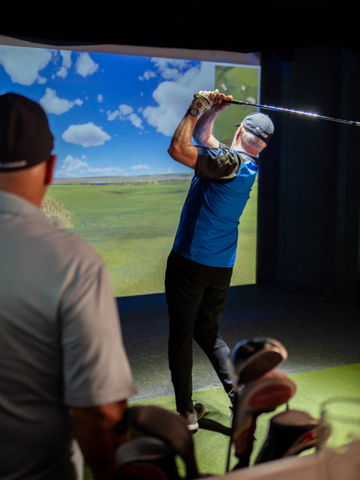 A golfer follows through on a drive in front of the 16.5-foot FullSwing simulator screen